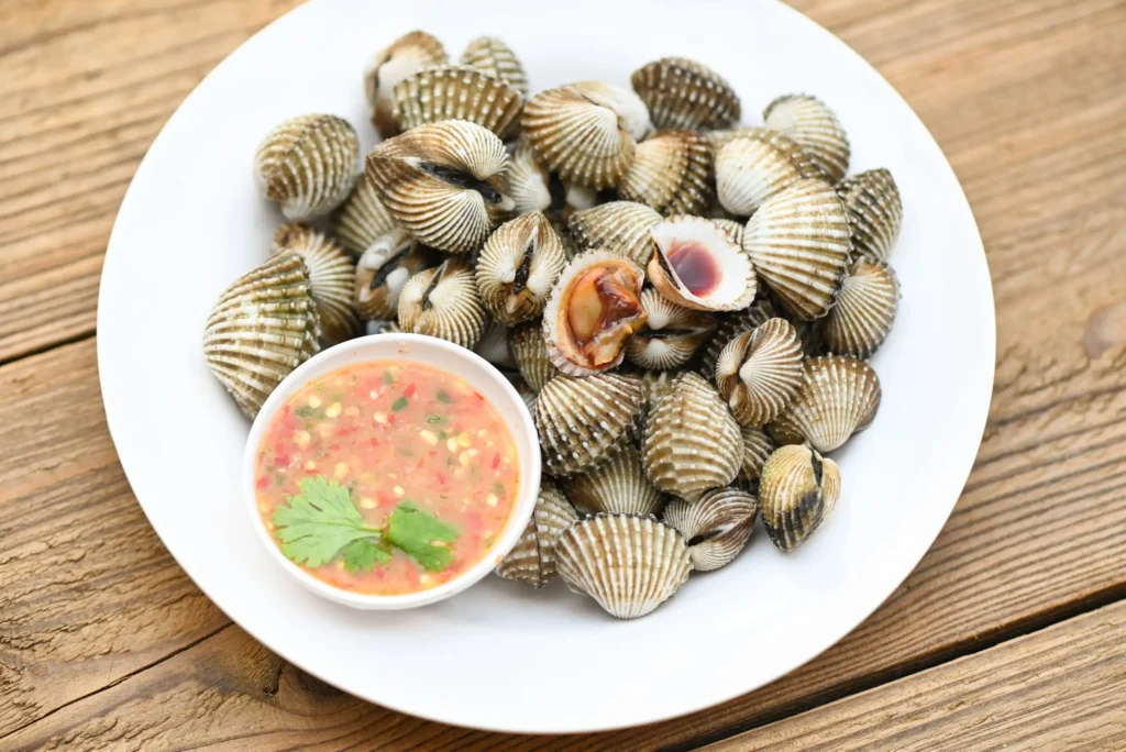 cockles-white-plate-with-seafood-sauce-table-background-fresh-raw-shellfish-blood-cockle-ocean-gourmet-seafood-restaurant (Web H)